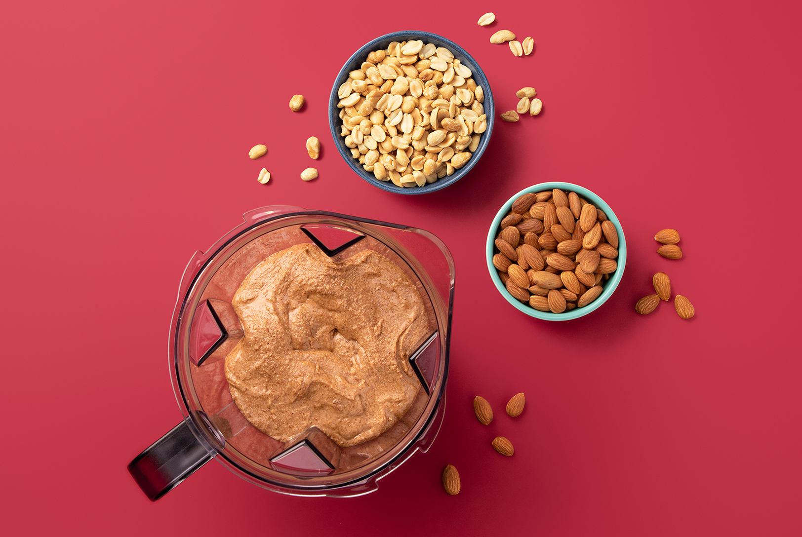 blended almond butter in a blender pitcher with almonds and peanuts